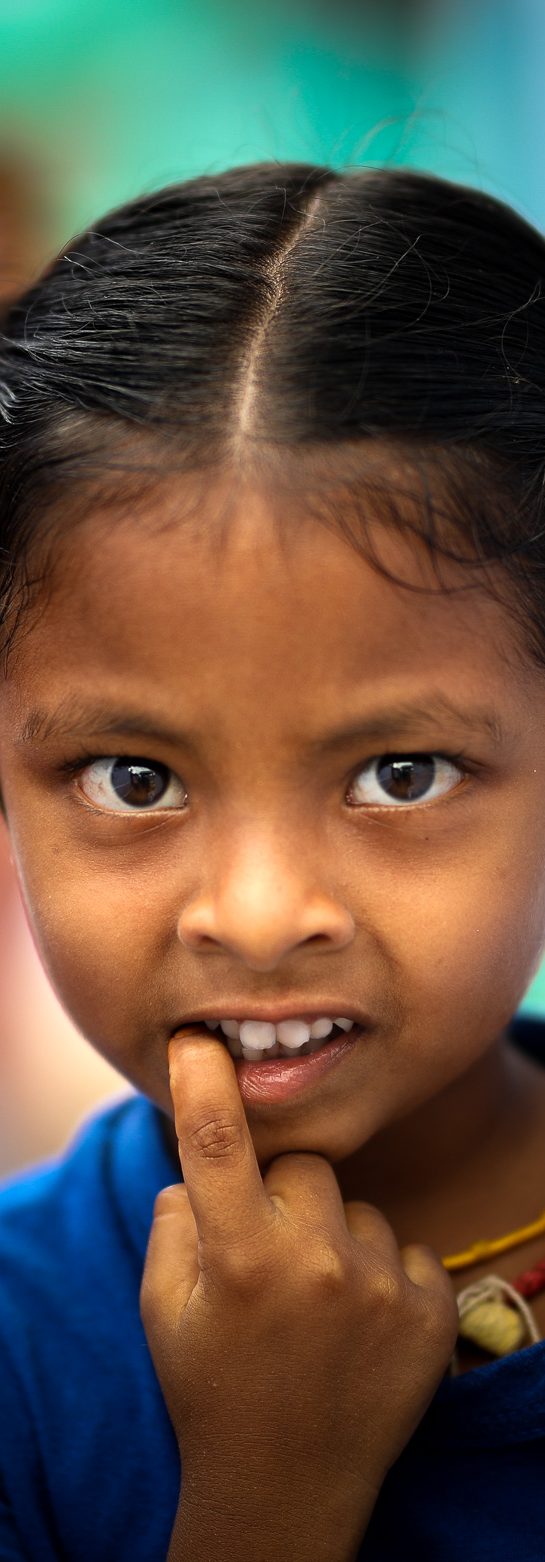 Portrait of a young girl in a blue T-shirt, finger to her lips